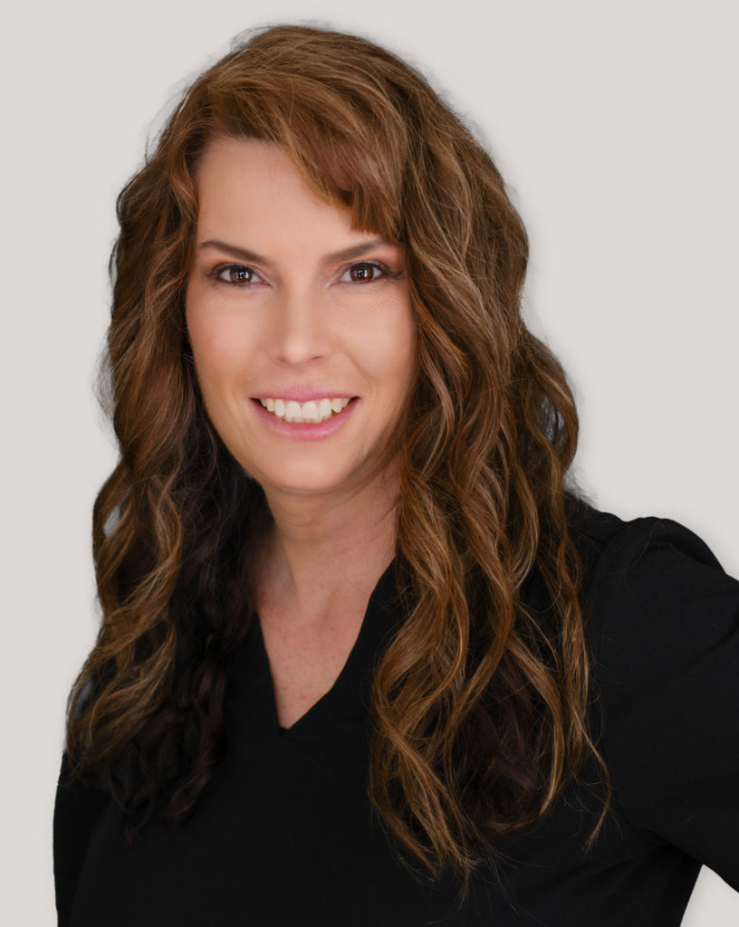 Portrait of Michelle Serpico smiling with soft curls and a professional appearance.