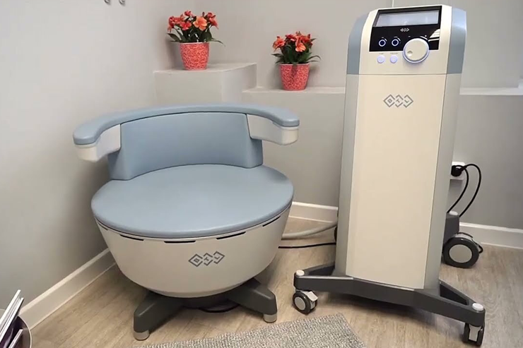 A medical device with a chair in front of it, possibly for non-invasive treatments.